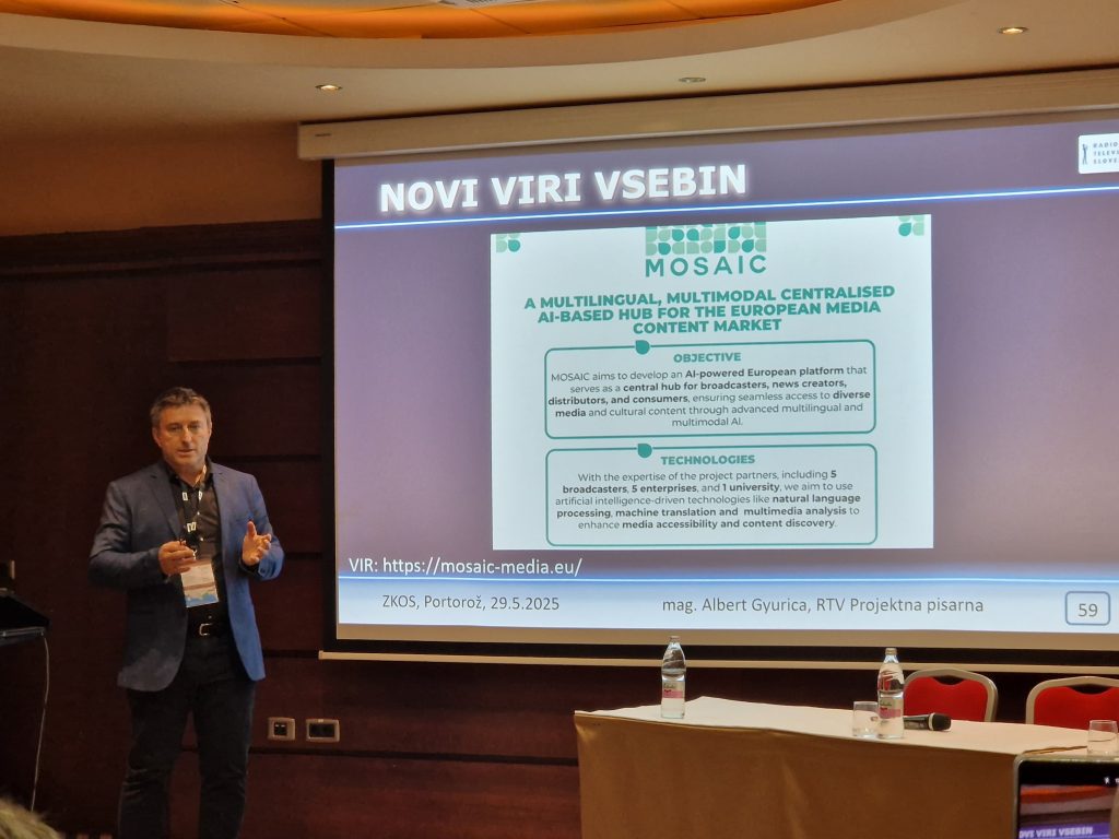Albert Gyurica from RTV Slovenija giving a presentation at the Slovenian Cable TV Association Program Conference in Portorož on 29 May 2025. He stands beside a screen showing a MOSAIC slide titled "Novi viri vsebin" (New Content Sources), describing MOSAIC as a multilingual, multimodal, AI-based hub for the European media content market. The slide outlines the platform’s objective and technologies, with a visible URL (https://mosaic-media.eu/).